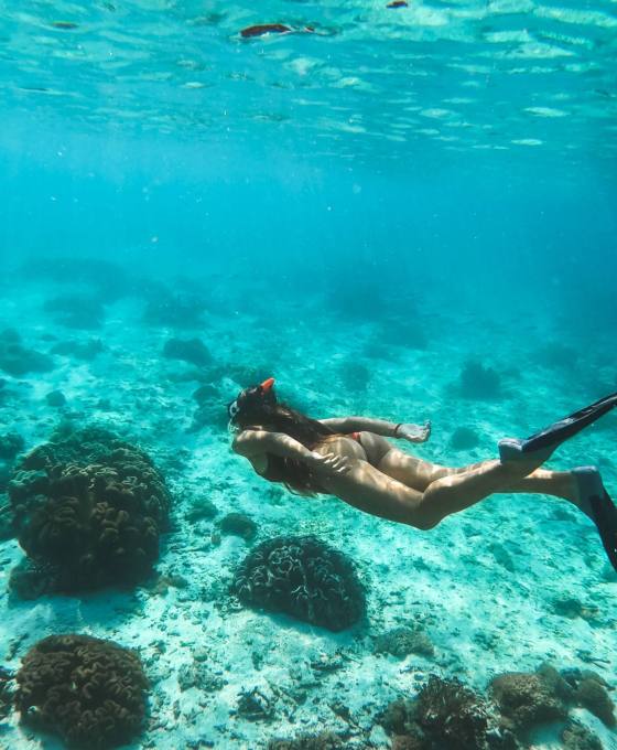 Woman snorkelling underwater with snorkel mask in clear transpar